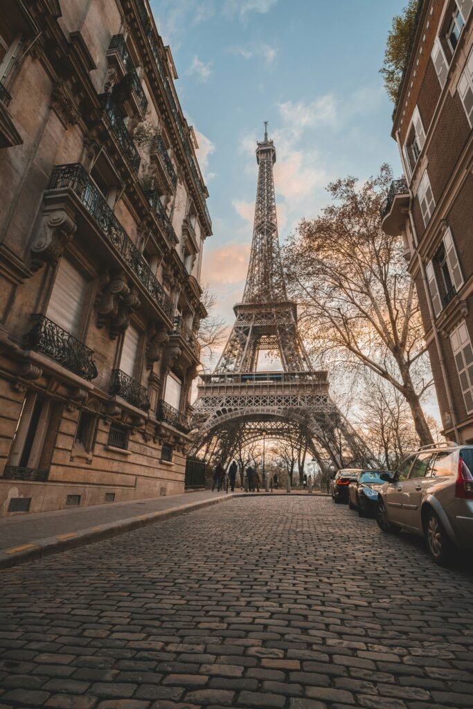 Eiffel Tower viewed from a cobblestone street between buildings in Paris, France.