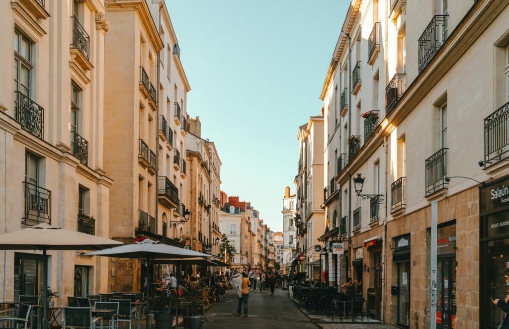 Street in Nantes, France, lined with historic buildings, outdoor cafés and pedestrians.